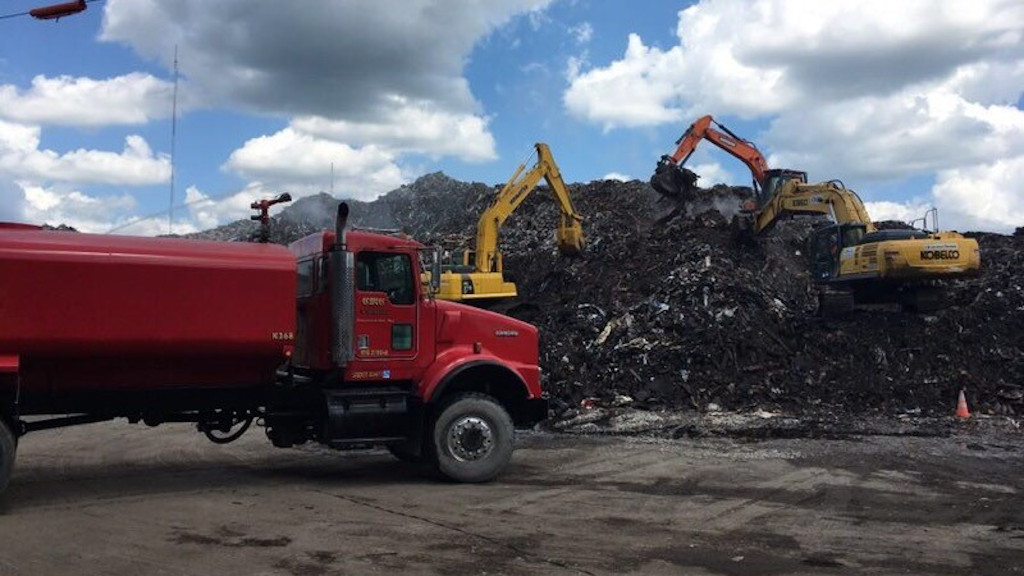 Large red truck by pile of refuse